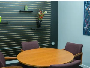 MicroOffice Solutions second conference room in Casper Wyoming with round wooden table, upholstered chairs, slatwall accent wall with flowers and cactus decor