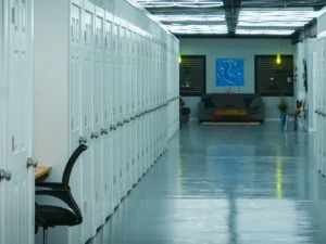 MicroOffice Solutions Casper Wyoming long hallway showing row of private numbered micro-office suite doors with open suite and chair visible and casual lounge area at far end